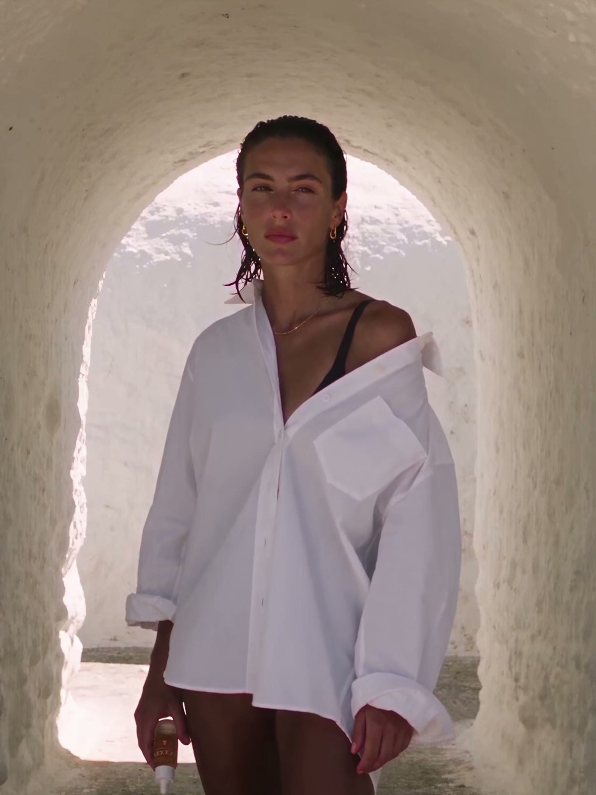 BODRIA model in a white shirt under a Mediterranean stone arch